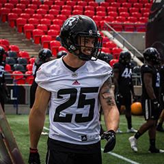 Brendan Gillanders in his football gear smiles during warmup on the field.