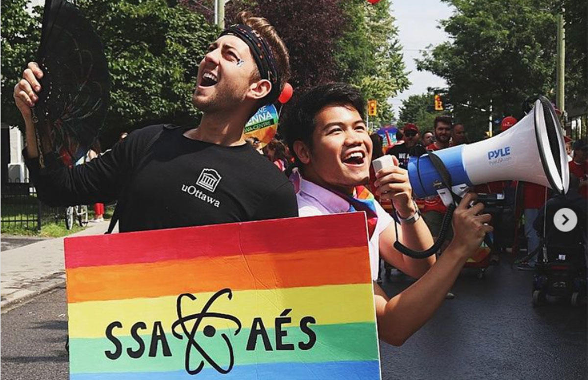 Jesse Lesniowski and Dasa Soekotjo holding a sign with the Pride rainbow and the Science Students’ Association's logo