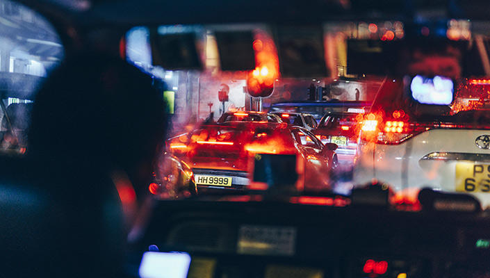 Lights from other cars seen through the front windshield of a taxi at night.