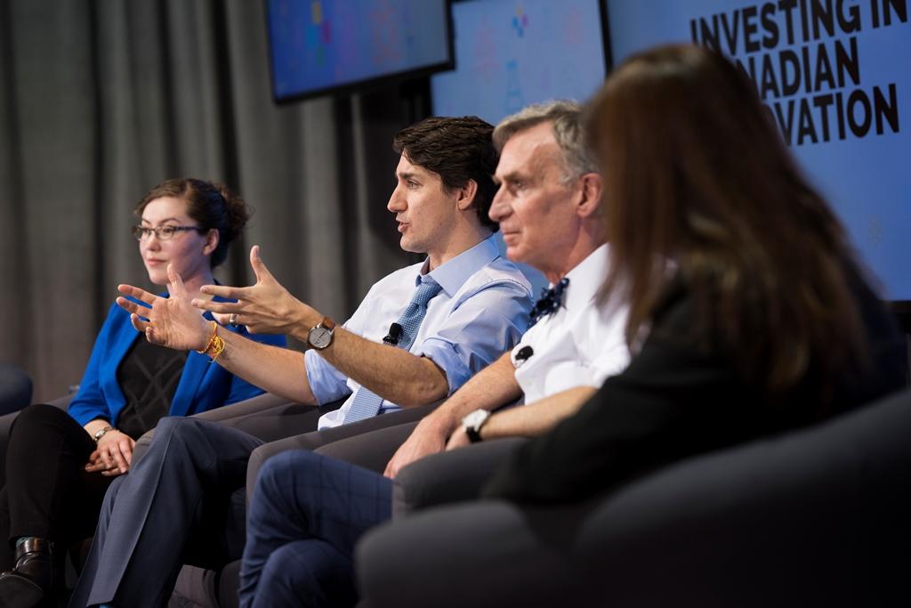 Prime Minister Justin Trudeau, sharing a stage with Bill Nye and two women, speaks to an unseen audience.