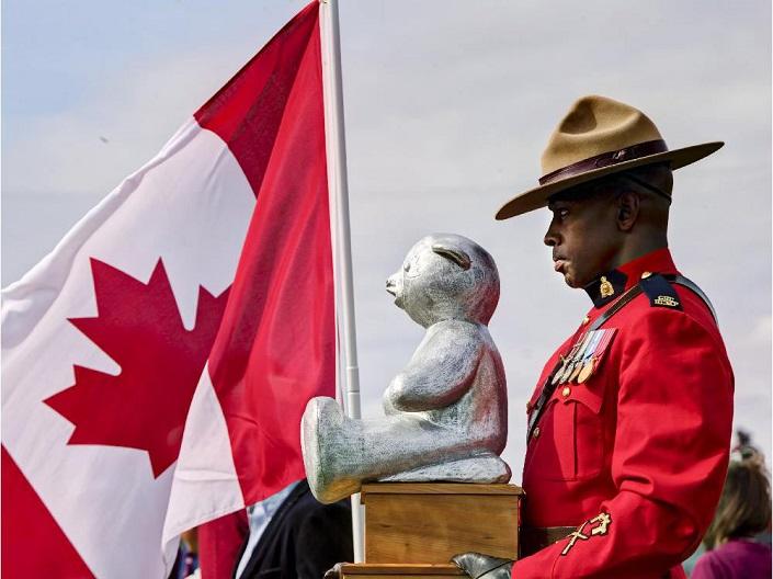 An RCMP officer carries the new Panda trophy onto the field.