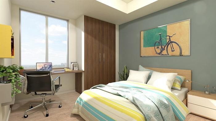 A sunny bedroom, with double bed, large window, desk and chair, and painting of a bicycle above the bed.