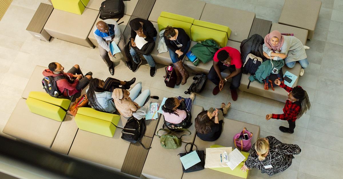 About a dozen students, seen from above, sitting together and chatting.