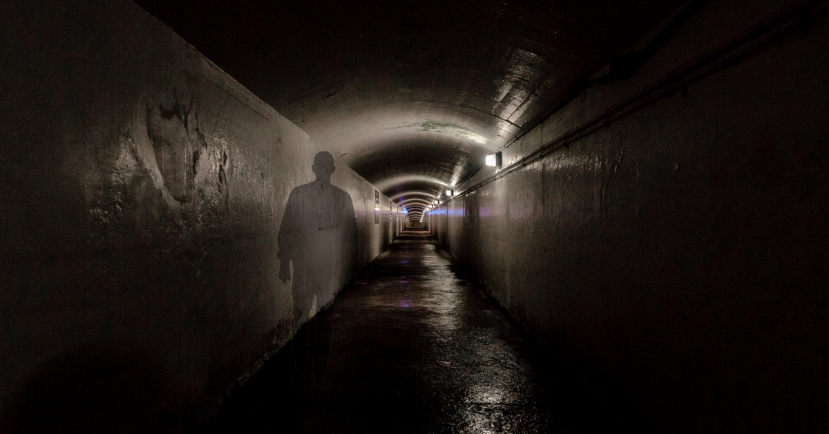 A tunnel with the shadow of a man cast on the wall.