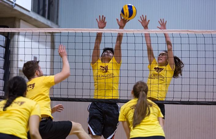 Five students energetically play volleyball.
