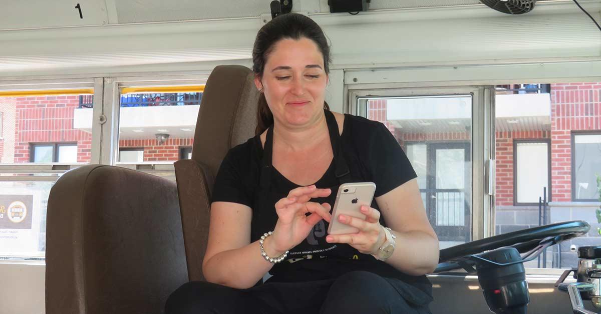 Anne donovan looking at her cell phone while sitting in the driver's seat.